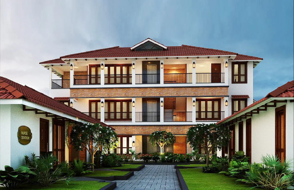 A modern senior living community featuring a three-story building with a traditional roof, surrounded by greenery and a pathway leading to a nurse station.