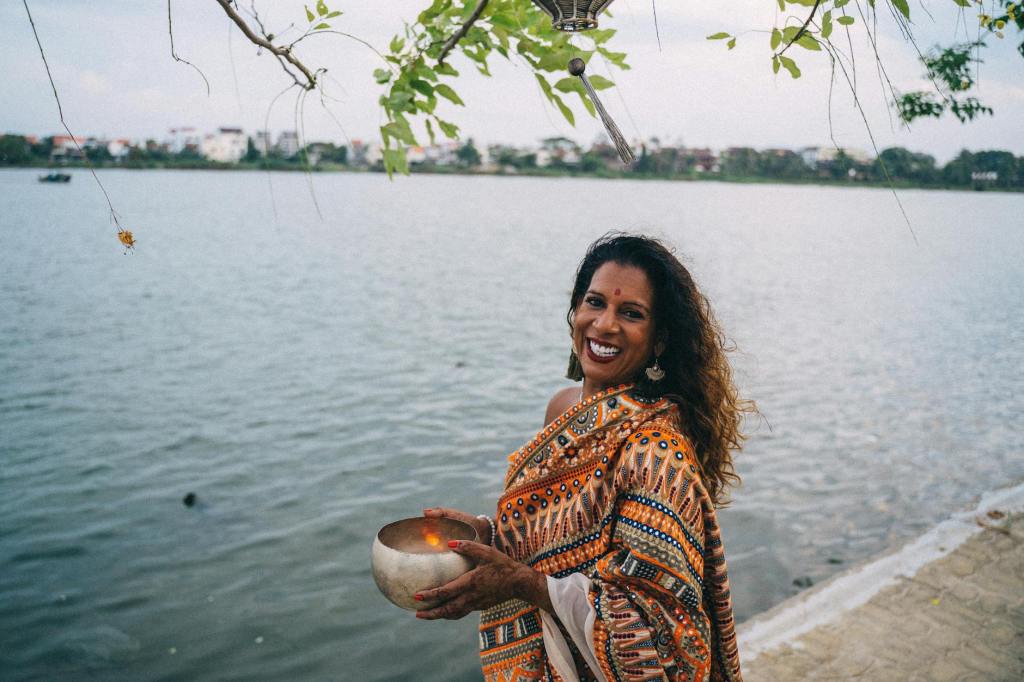 a woman in printed saree standing near the body of water