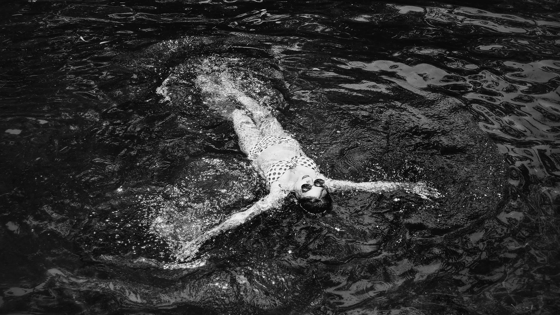 a grayscale of a woman floating on a water