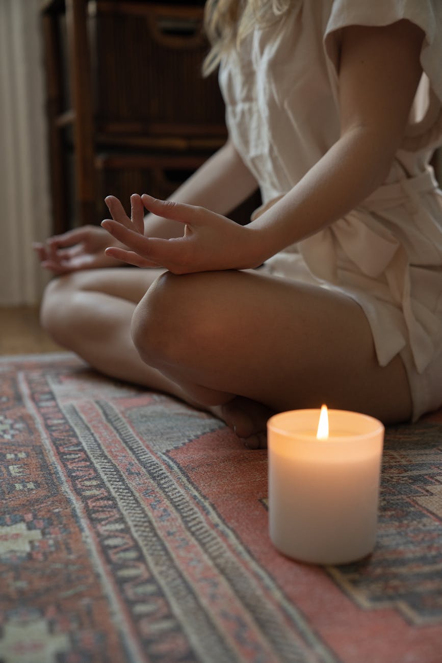 woman meditating next to a burning candle